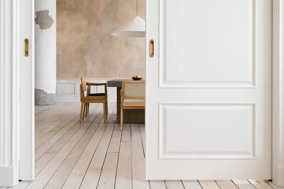 Puertas blancas y suelo de madera clara crean un ambiente acogedor. La combinación de suelo y puertas es sutil y elegante.