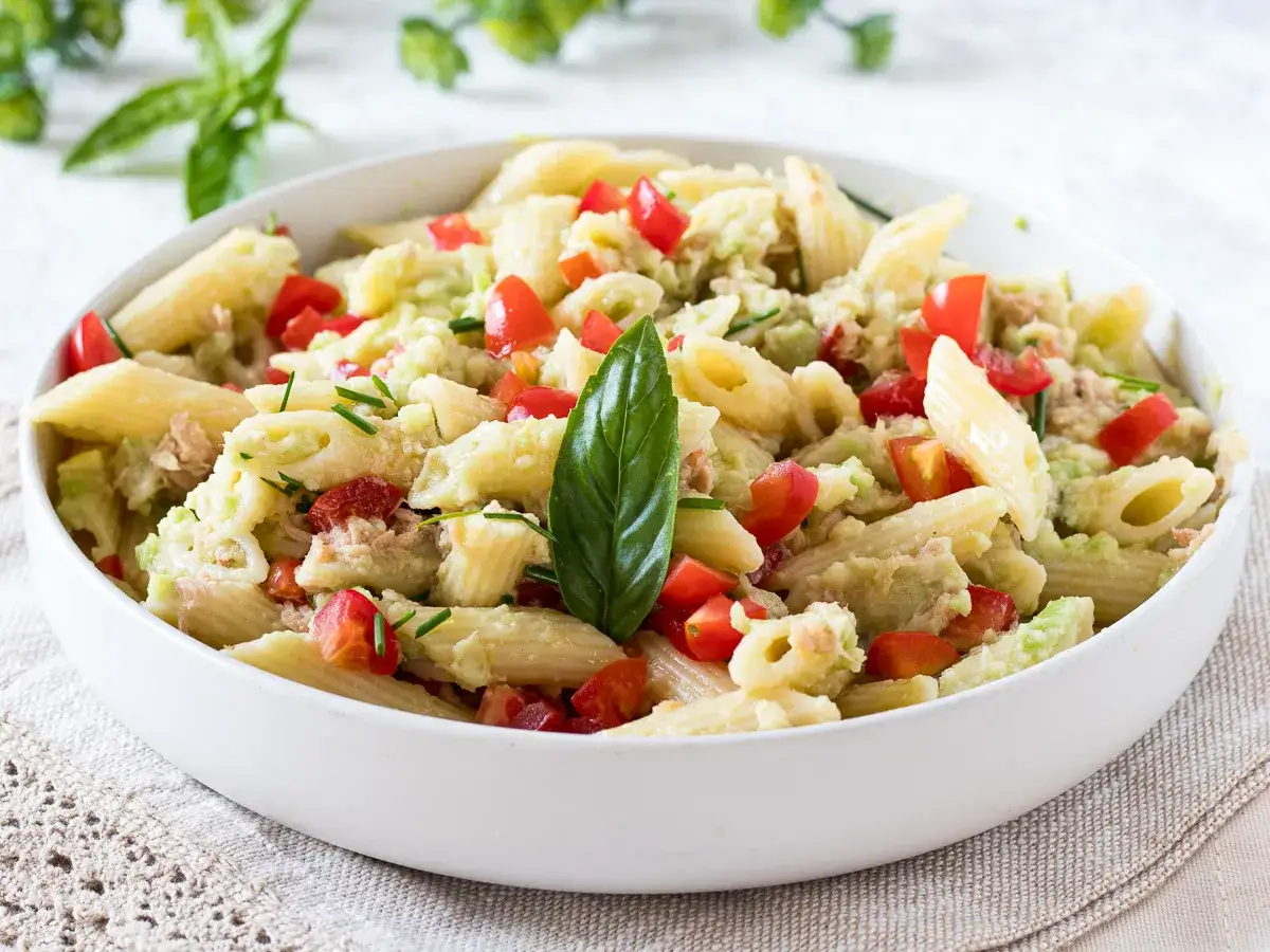 Penne con tonno e avocado, un piatto fresco e colorato con pomodorini e basilico.
