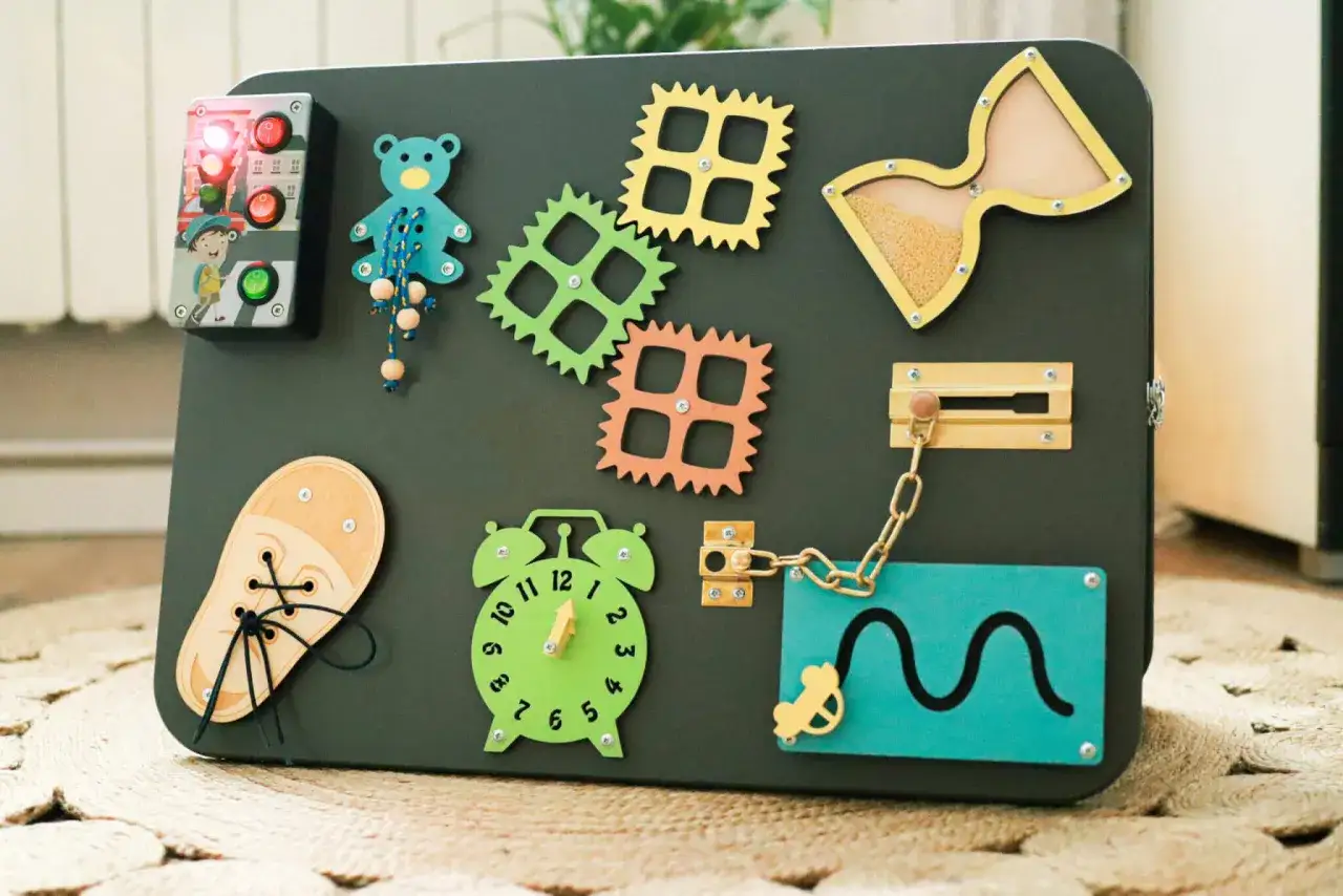 DIY tablica manipulacyjna z misiem, zegarem, zapięciami i elementami do nauki sznurowania.