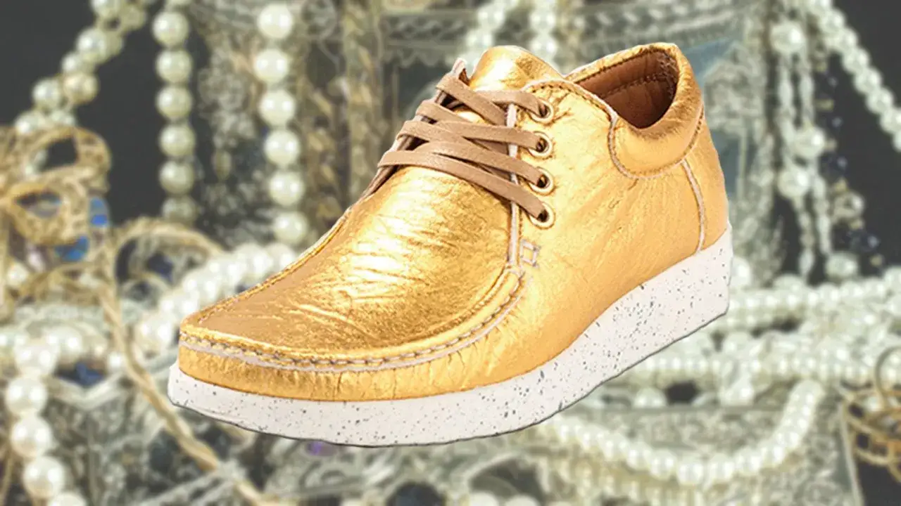 Goldene Ananasleder Schuhe, gl&auml;nzend und luxuri&ouml;s, umgeben von Perlen und Sch&auml;tzen.