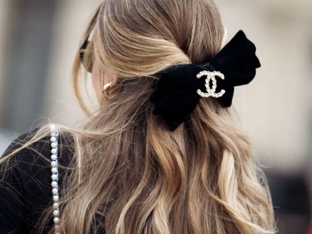 Elegancka kokarda z logo Chanel zdobi falujące włosy w odcieniu ciepły blond.