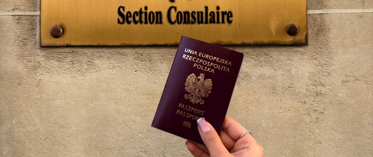 Dłoń trzyma polski paszport przed tabliczką 