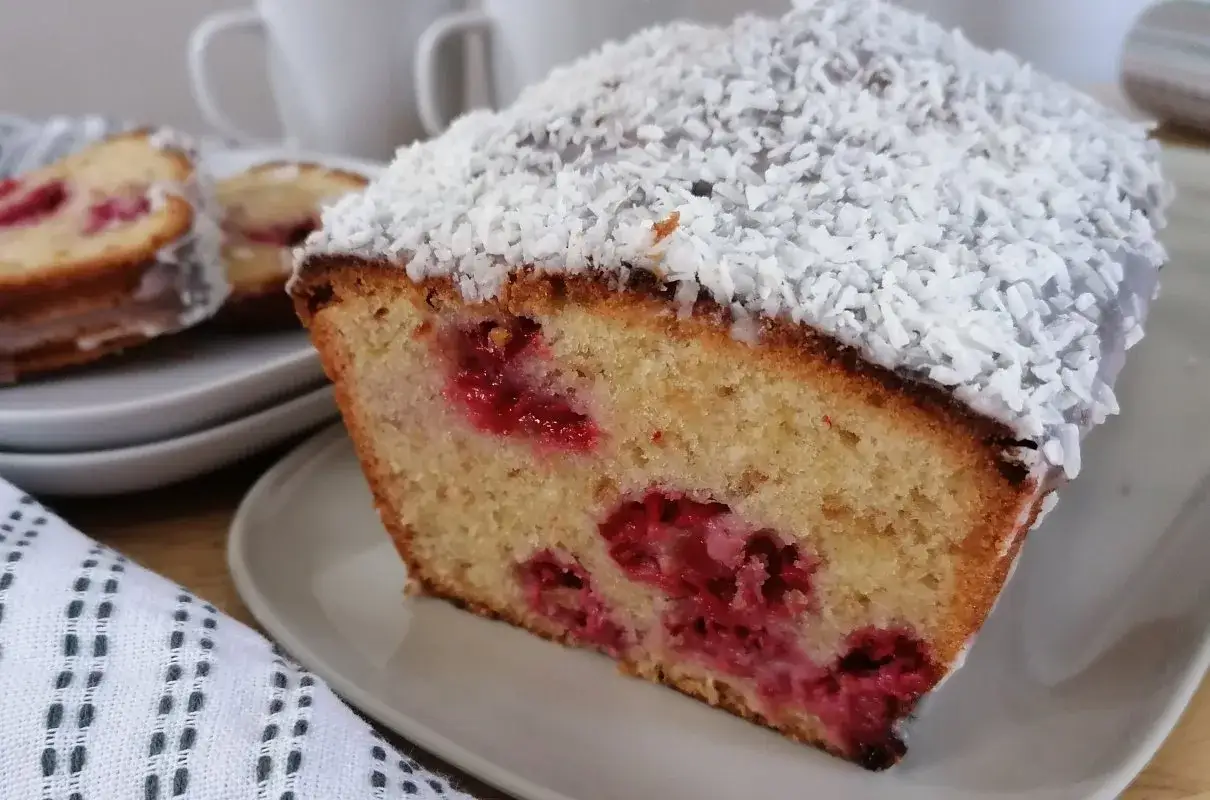Puszyste ciasto z mąki kokosowej z malinami, posypane wiórkami kokosowymi. Idealne na deser.