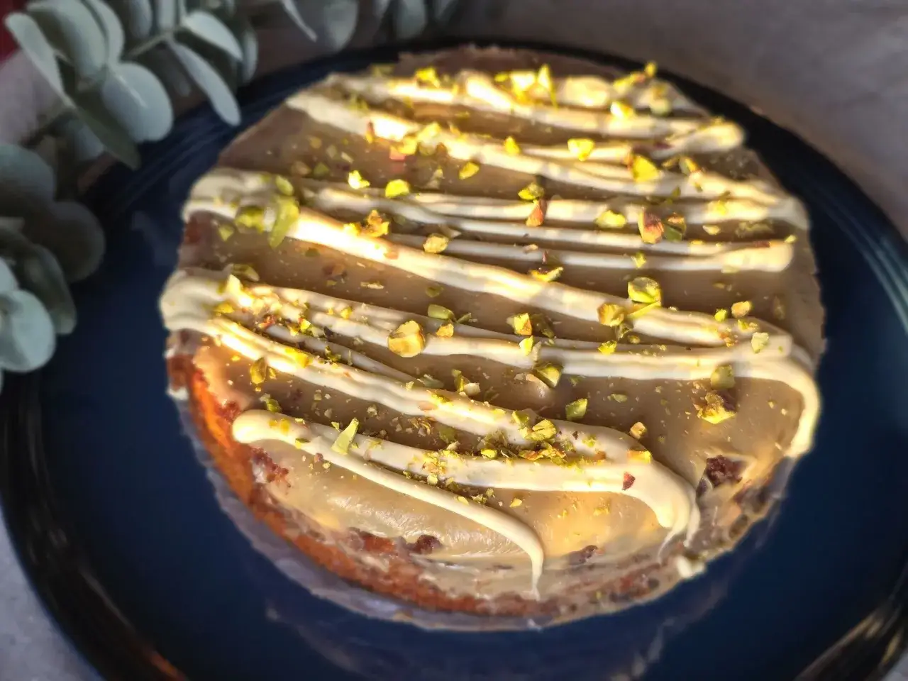 En läcker torta caprese med vit chokladglasyr och hackade pistagenötter.