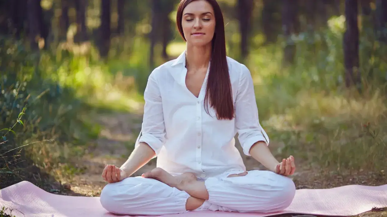 Mujer meditando en el bosque, un momento de paz para el crecimiento personal y espiritual.
