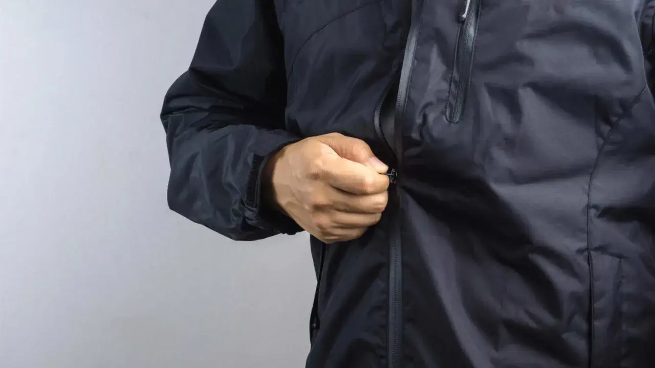 Mężczyzna zapina czarną kurtkę softshell. Dowiedz się, jak prać softshell, by zachował swoje właściwości.