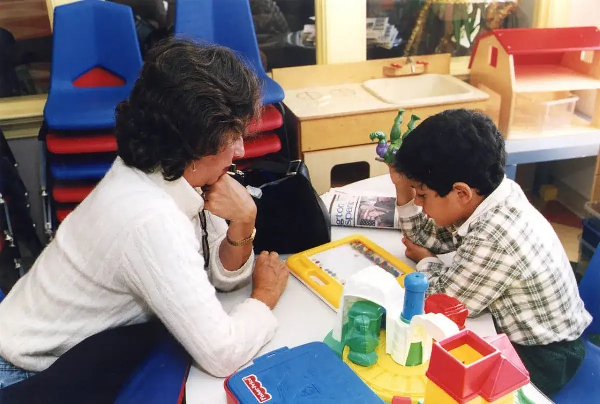 Una maestra ayuda a un niño con TDAH a concentrarse en un juego.