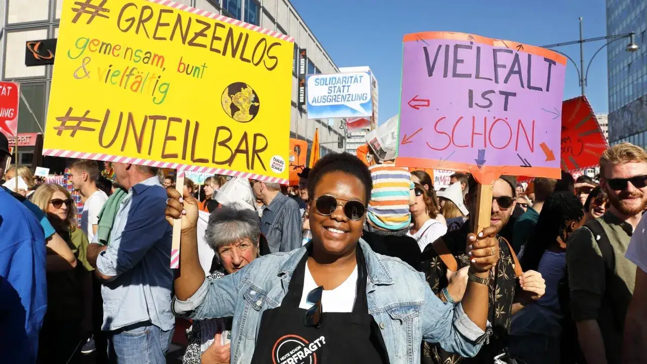 Menschen demonstrieren f&uuml;r Vielfalt und Solidarit&auml;t. Die Frage, ob Deutschland ein Einwanderungsland ist, wird durch die Plakate 