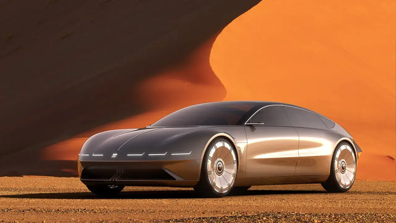 Futurystyczny Audi A9 sunący przez pustynię. Jego lśniące linie odbijają pomarańczowe wydmy.