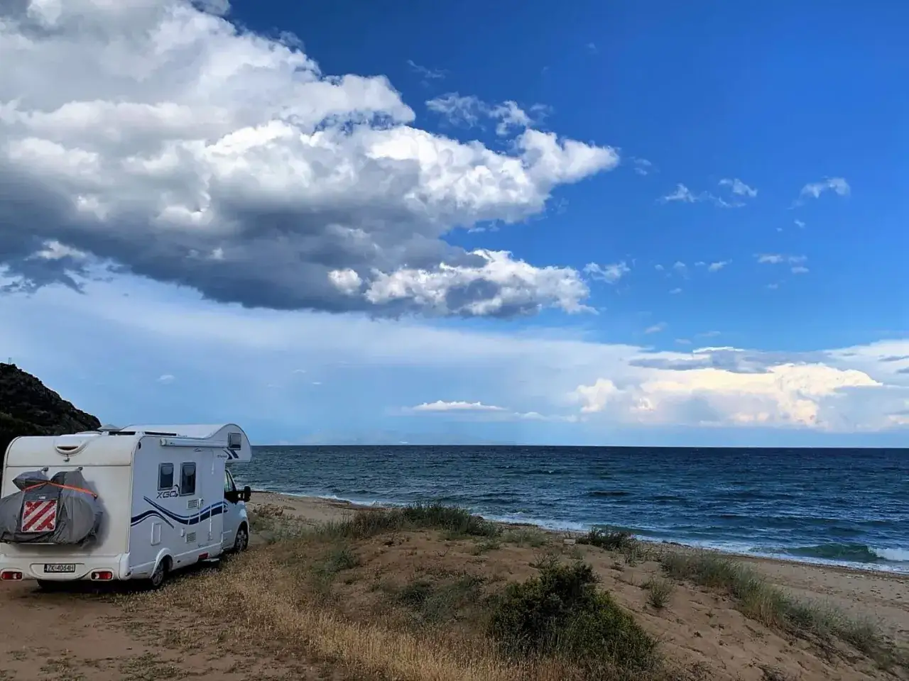 Kamper na plaży nad morzem, chmury na niebie. Idealne miejsce na wakacje w stylu naturyzm Polska.