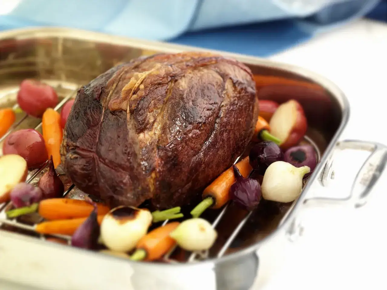 Ein 1,5 kg Rinderbraten schmort mit Wurzelgemüse in einer Bratreine.