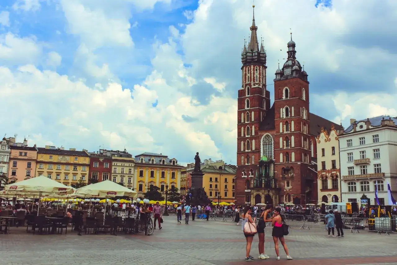 Tłum ludzi na Rynku Głównym w Krakowie, podziwiający Bazylikę Mariacką. Stare miasto Kraków tętni życiem.