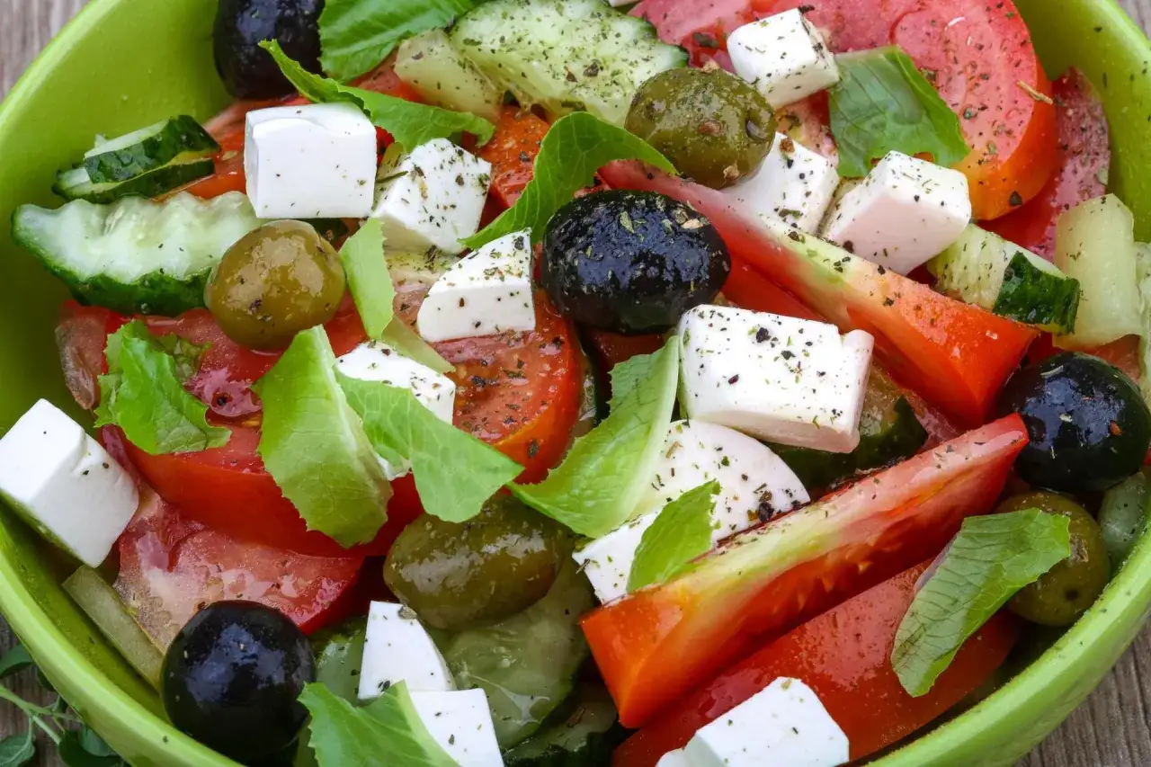 Sałatka grecka z kostkami sera feta, pomidorami, ogórkiem, oliwkami i ziołami. Ser feta właściwości odżywcze sprawiają, że to zdrowa i pyszna przekąska.