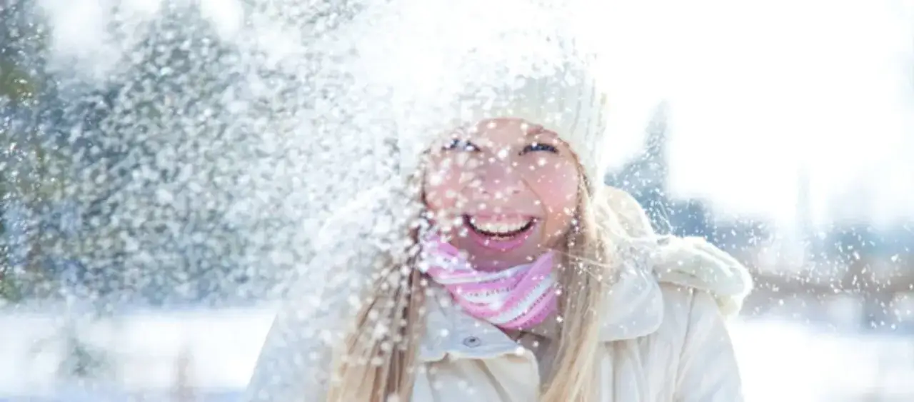 Glad tjej i sn&ouml;fall, med m&ouml;ssa och halsduk. Solskydd p&aring; vintern &auml;r viktigt, &auml;ven n&auml;r det sn&ouml;ar!