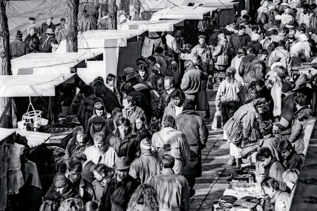 Tłum ludzi na bazarze, przypominającym atmosferę planu Balcerowicza. Ludzie kupują i sprzedają różne przedmioty, tworząc żywy obraz tamtych czasów.