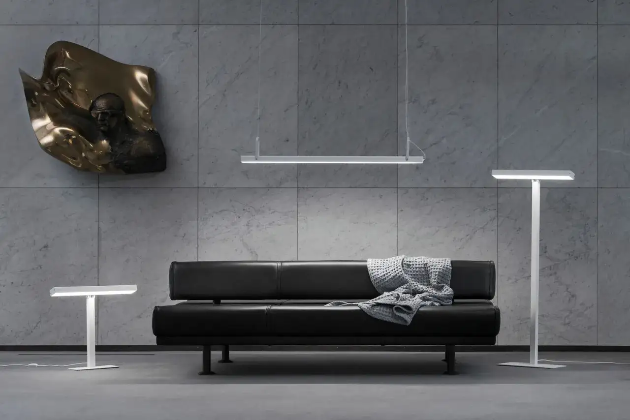 Modern lounge med svart soffa, konstverk och lampor. En hyllning till Harri Koskinens design.
