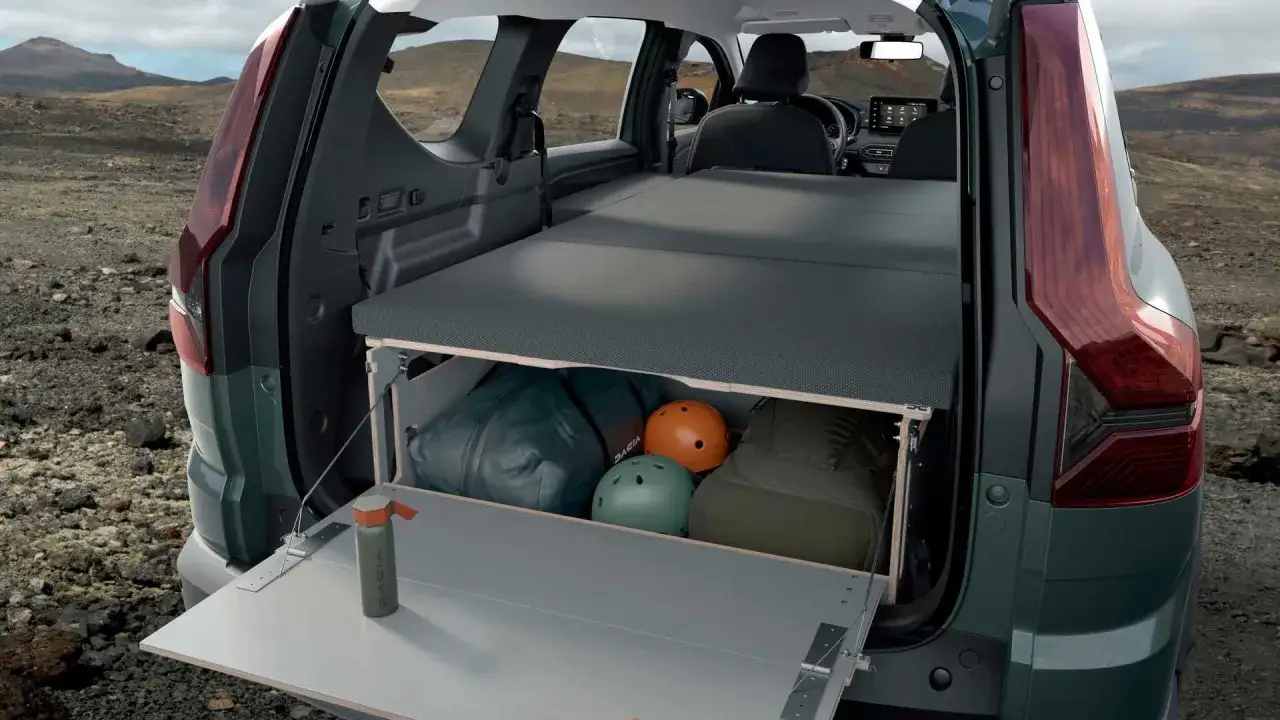 Wnętrze Dacia camper z rozłożonym łóżkiem i schowkami na bagaże, kaski i butelkę. Gotowy na przygodę!