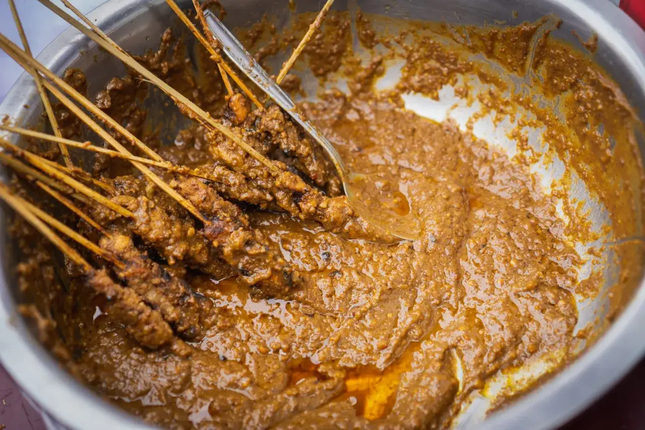 Brochettes de poulet baignant dans une sauce satay cr&eacute;meuse et riche, pr&ecirc;te &agrave; &ecirc;tre d&eacute;gust&eacute;e.