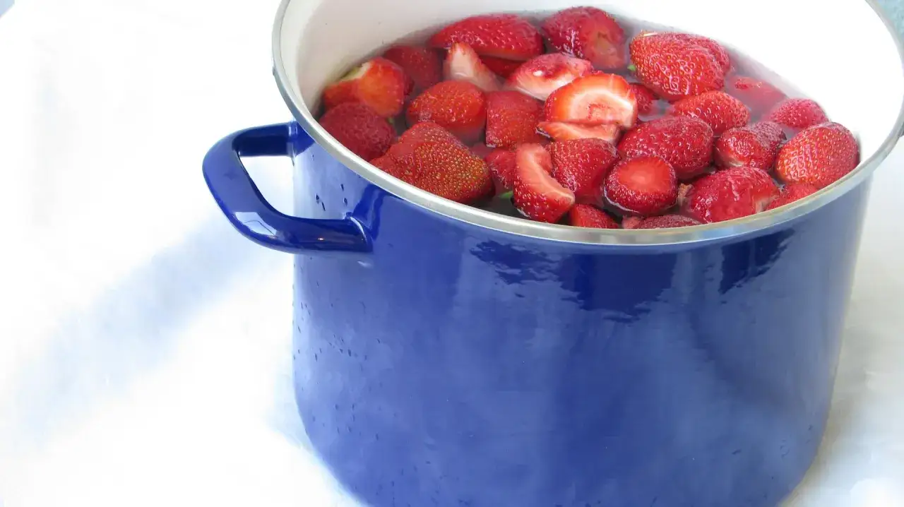 Ein blauer Topf voller frischer Erdbeeren, bereit f&uuml;r die Zubereitung von Marmelade ohne Zucker.
