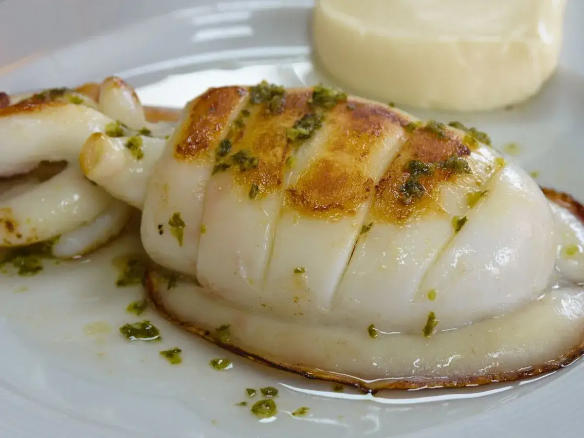 Sepia a la plancha, dorada y jugosa, con un toque de hierbas verdes. Un plato delicioso y fresco.
