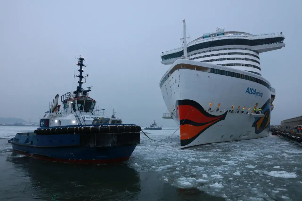 Gdynia: potężny statek wycieczkowy AIDAprima i holownik w lodowatej wodzie.