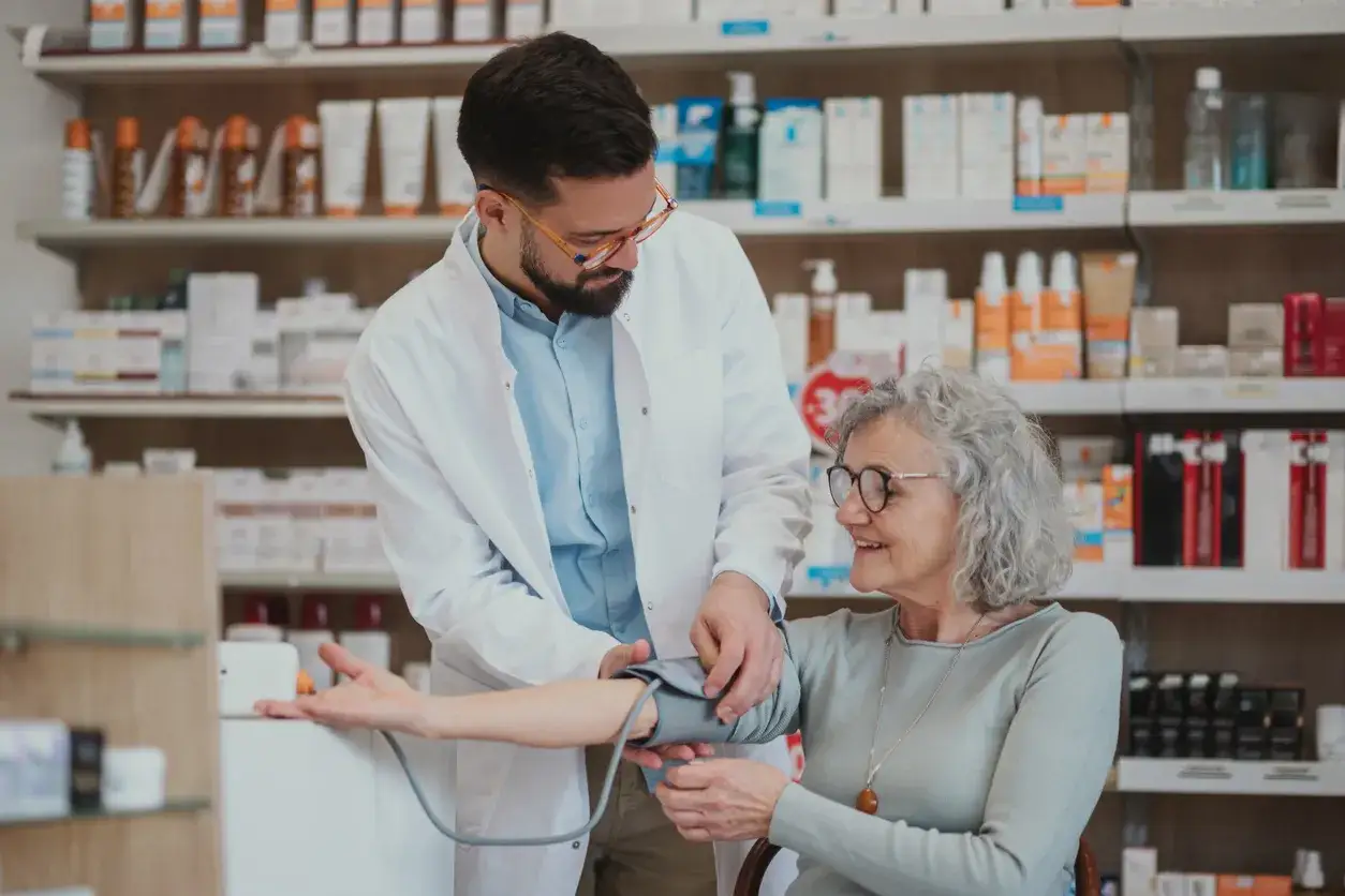 Farmaceuta mierzy ciśnienie starszej kobiecie. Wynik: ciśnienie 135 na 85.