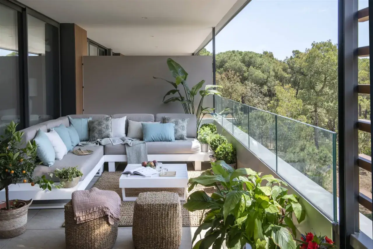 Elegante diseño terraza exterior con sofá modular, mesa de centro y abundante vegetación.