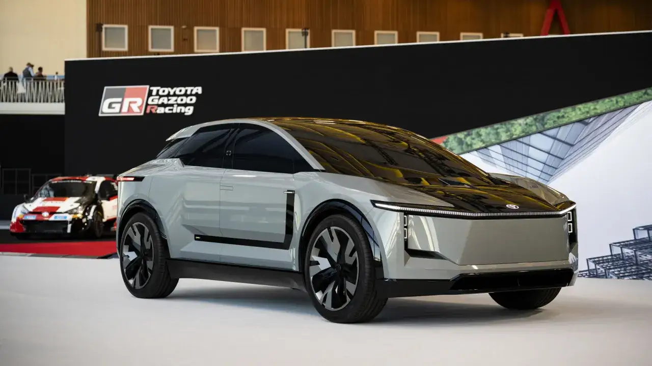 Concept car grigio futuristico, con un'auto da corsa Toyota Gazoo Racing sullo sfondo. Nuovi modelli Toyota in arrivo.