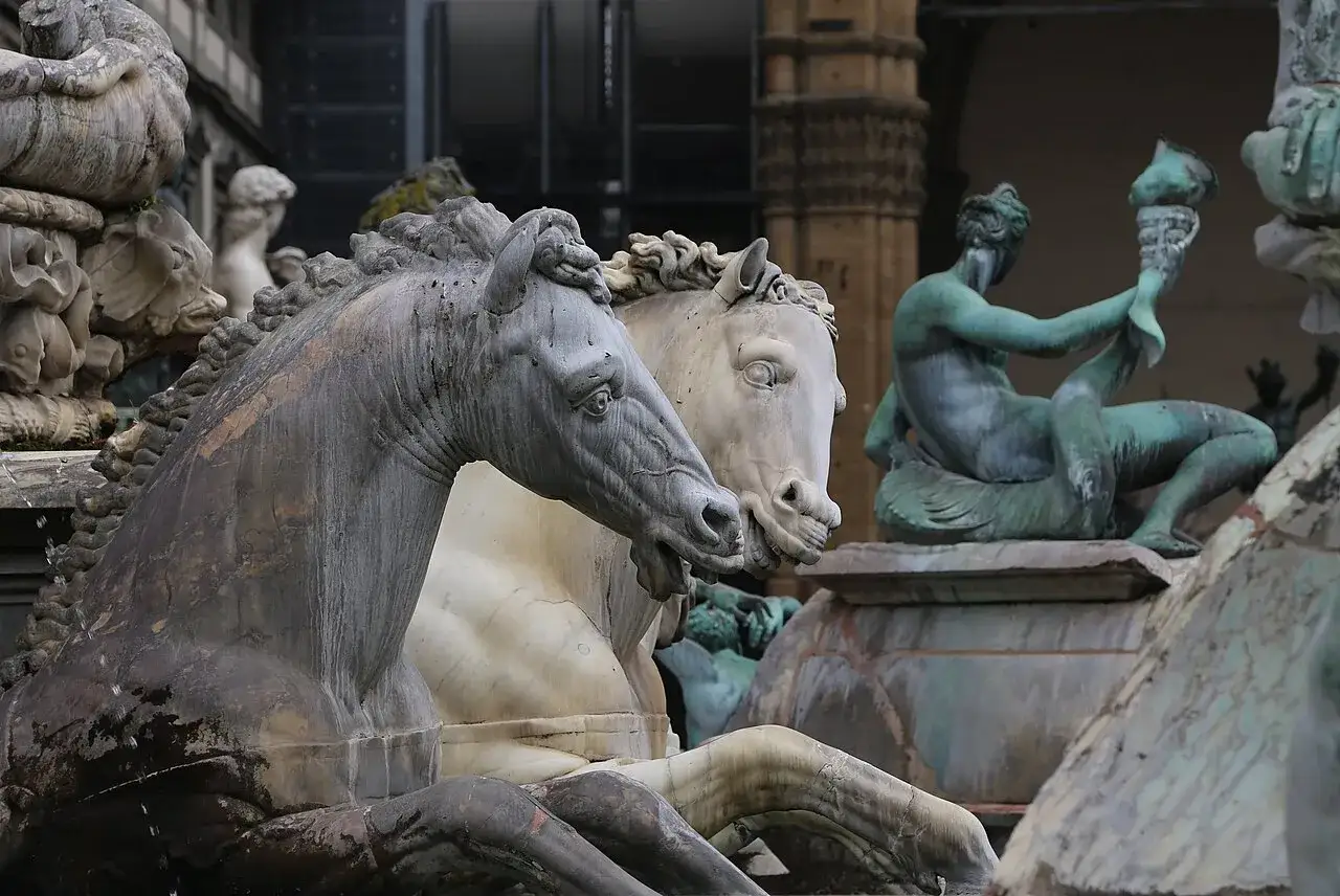 Cavalli di marmo e bronzo nella Fontana di Nettuno a Firenze, con figure mitologiche sullo sfondo.