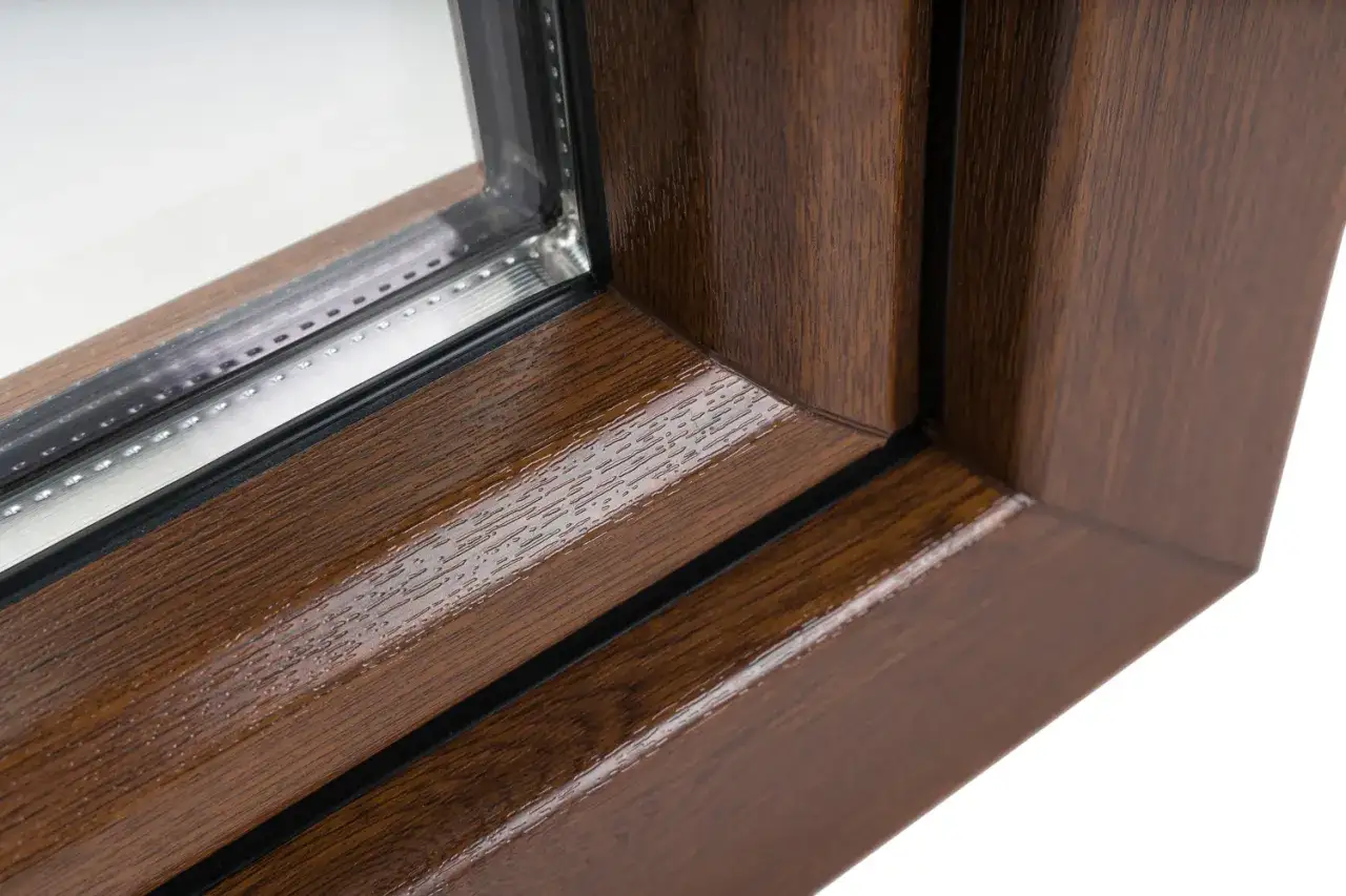 Gros plan sur le coin d'une fenêtre. Le cadre présente une texture de bois réaliste dans une riche couleur fenetre bois.