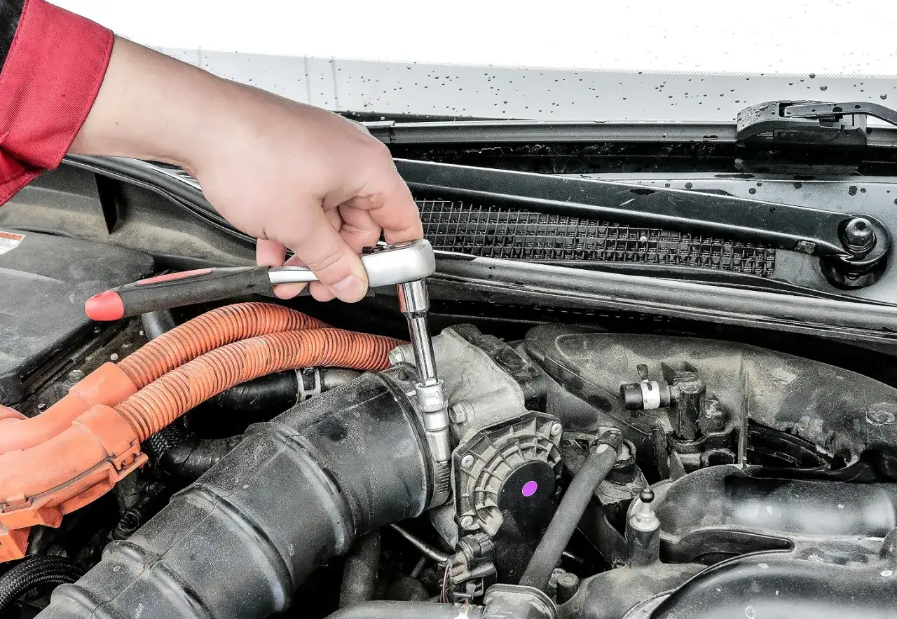 Ręka mechanika dokręca śrubę kluczem nasadowym. To część procesu, jak sprawdzić katalizator w benzynie, gdy jest on uszkodzony.