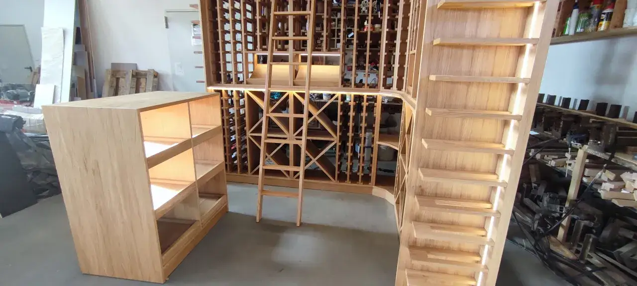 Drewniane piwniczki na wino, z regałami i drabiną, czekają na wypełnienie najlepszymi trunkami.