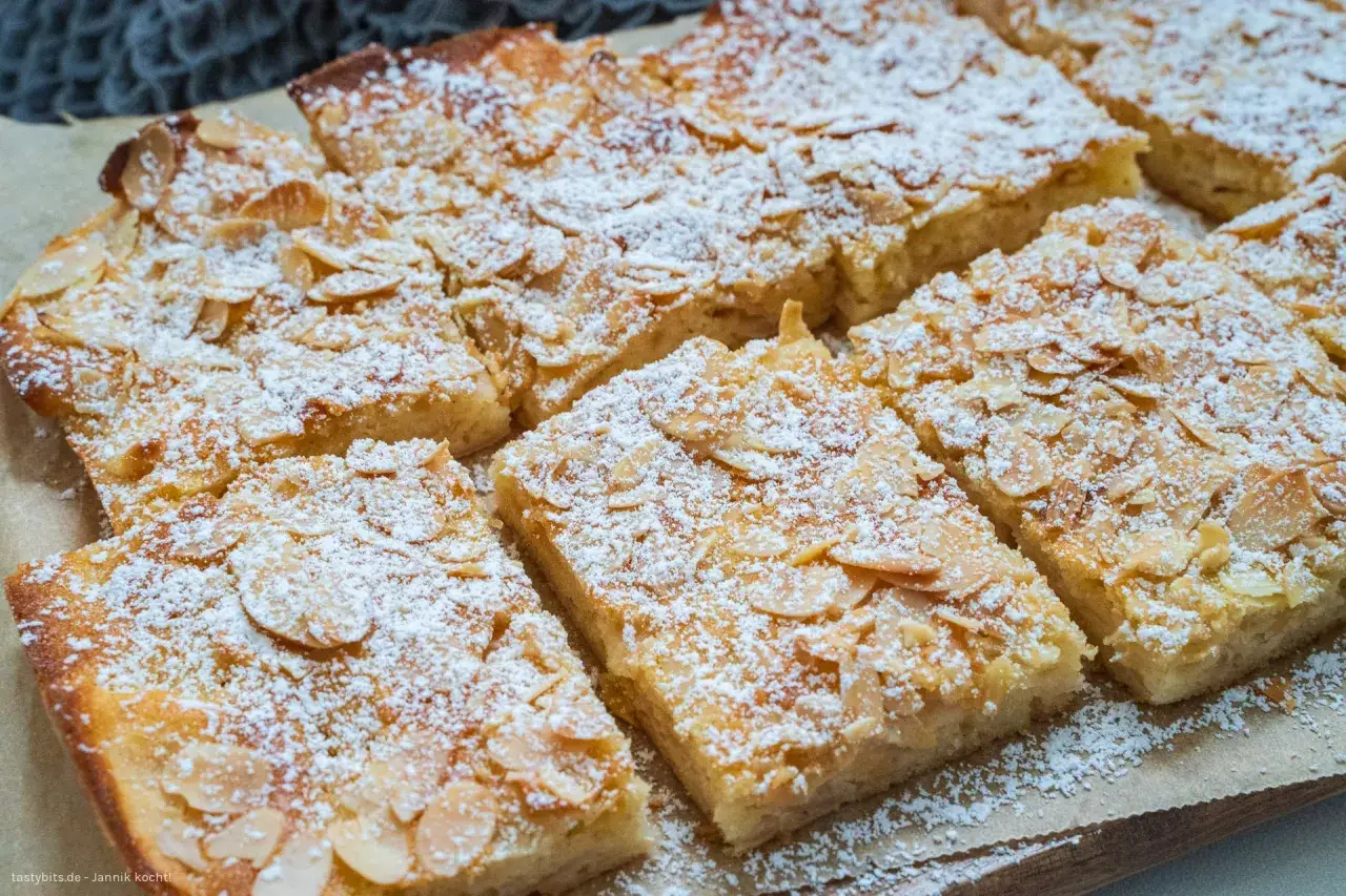 Saftiger Apfelkuchen vom Blech, bestreut mit Puderzucker und Mandelbl&auml;ttchen. Ein Genuss f&uuml;r jeden Anlass!