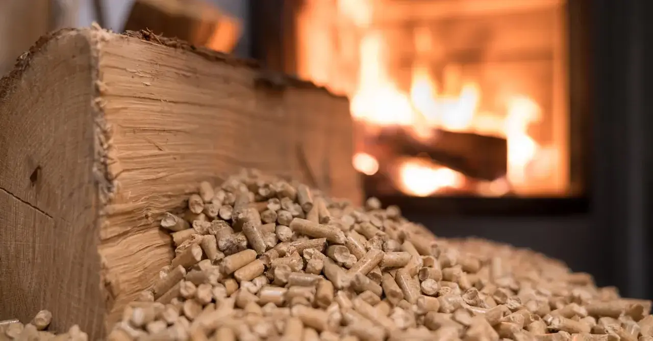 Bûche de bois et granulés à côté d'un feu de cheminée. Le pouvoir calorifique du pellet assure une chaleur constante.