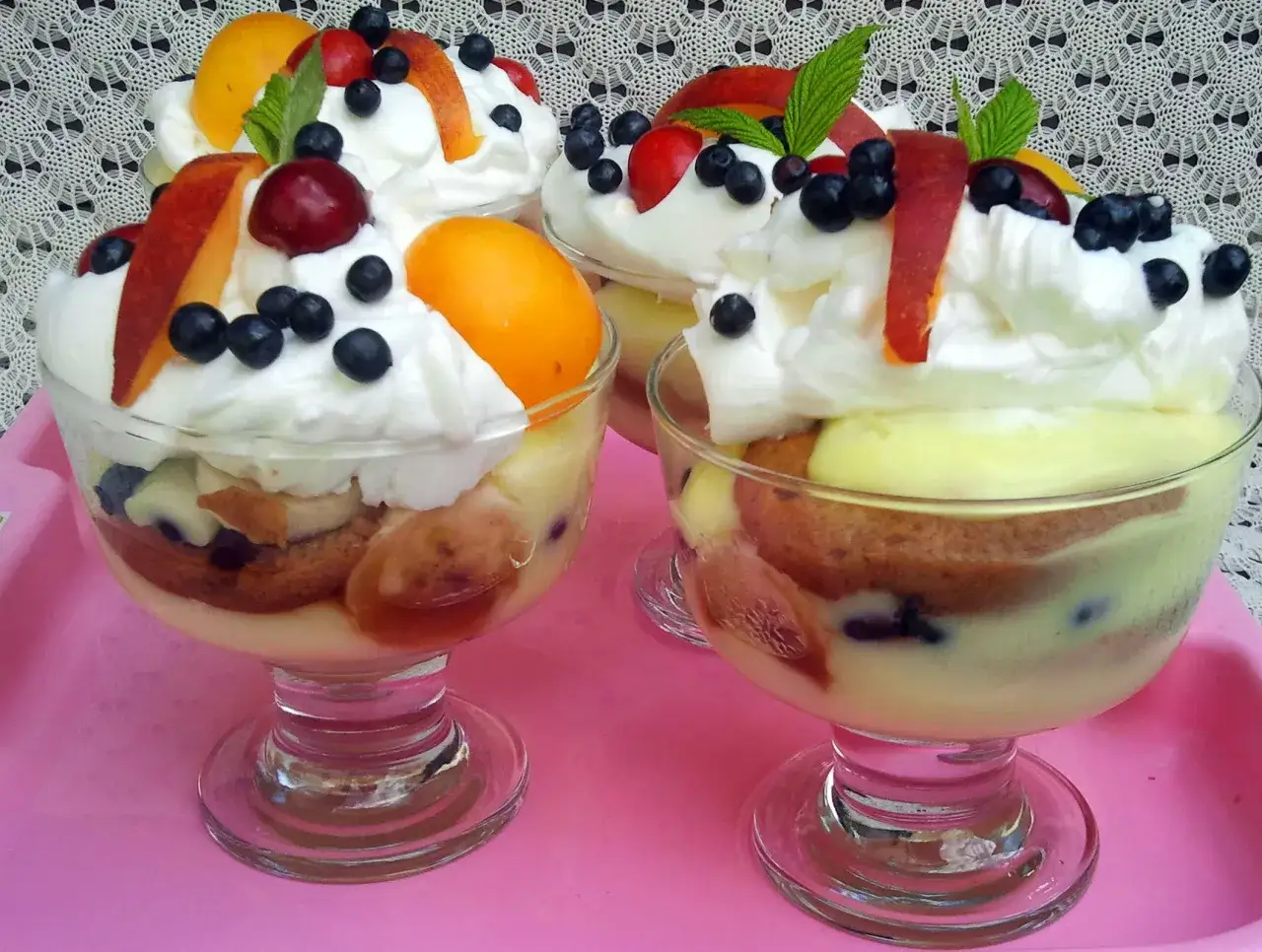 Pyszny deser w pucharkach: warstwy biszkoptu, owoców i bitej śmietany. To właśnie custard, czyli krem budyniowy, nadaje mu aksamitną konsystencję.