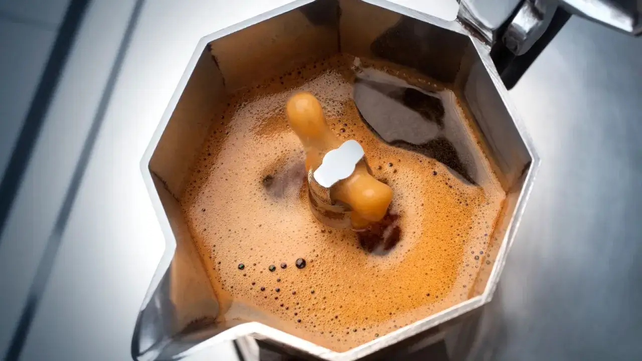 Caffè americano con la moka: la schiuma dorata sale dal beccuccio, pronto per essere gustato.