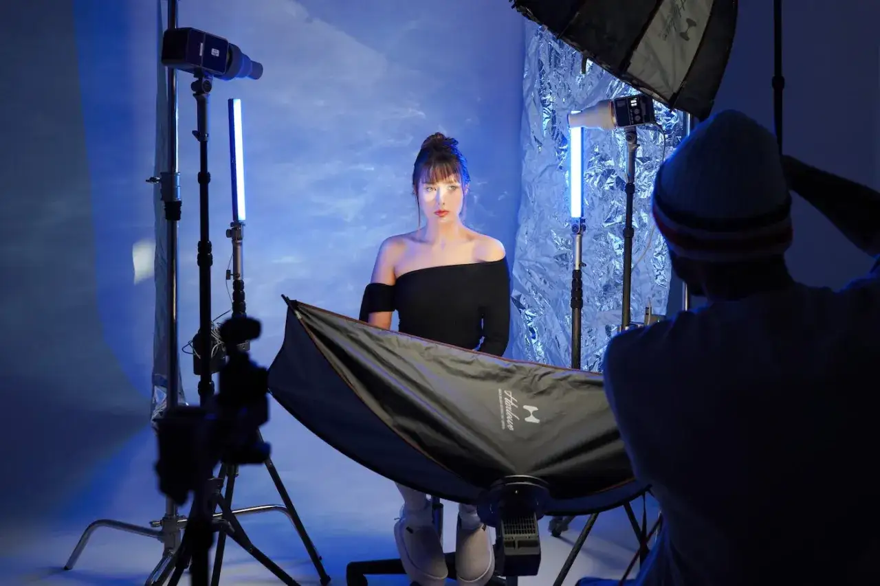 Creative led light photography ideas in action: a model poses with blue lights, a photographer adjusts gear.