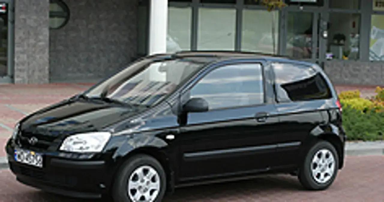 Czarny Hyundai Getz 1.1, miejski samochód z trzydrzwiowym nadwoziem, zaparkowany przed budynkiem.