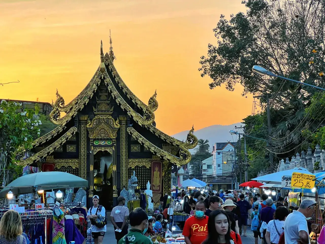 Wieczorny targ w Chiang Mai. Złota świątynia, stragany z ubraniami i tłumy ludzi tworzą niepowtarzalne **chiang mai atrakcje**.