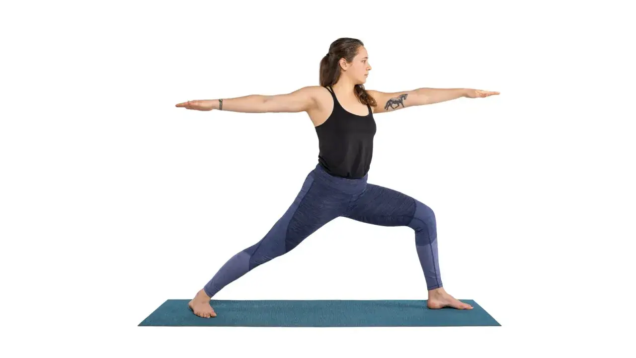 Donna in posa Virabhadrasana 2, con braccia tese e sguardo fiero.