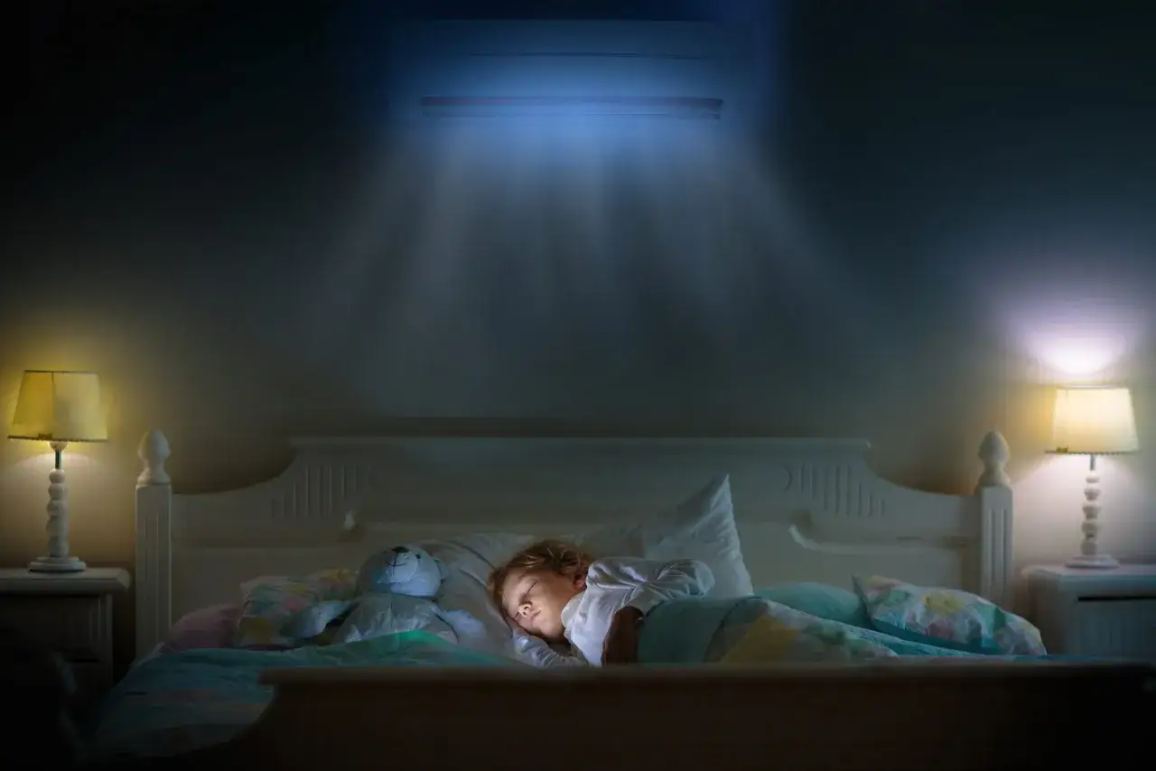 Niño duerme plácidamente bajo el aire acondicionado, disfrutando de un sueño fresco y reparador.