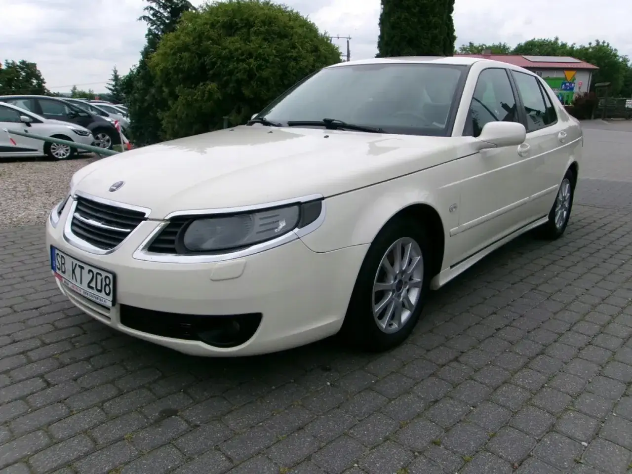 Biały sedan Saab 9-5 na brukowanym placu. Eleganckie samochody Saab, klasyka motoryzacji.