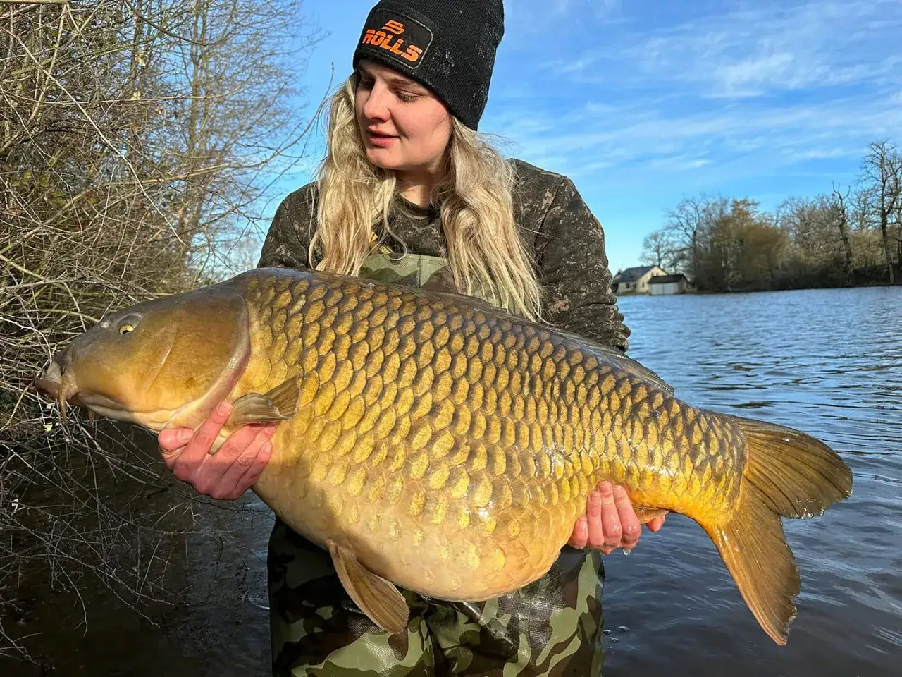 Eine Anglerin h&auml;lt stolz einen riesigen Karpfen am Paylake in Frankreich.
