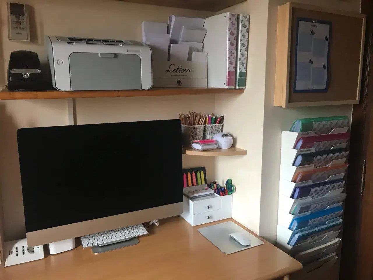 Scrivania ordinata con computer, stampante e organizer per documenti. Un esempio di come organizzare i documenti di casa con cartelline colorate e raccoglitori.