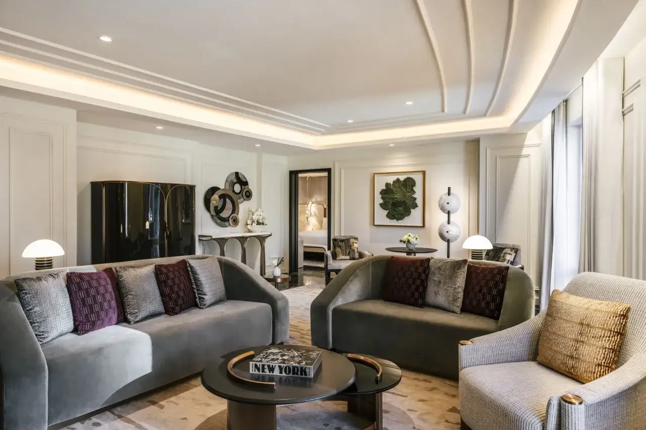 Elegancki salon z szarymi sofami, ozdobnymi poduszkami i czarną szafką. To wnętrze, jak z najdroższego hotelu na świecie, zaprasza do luksusowego wypoczynku.