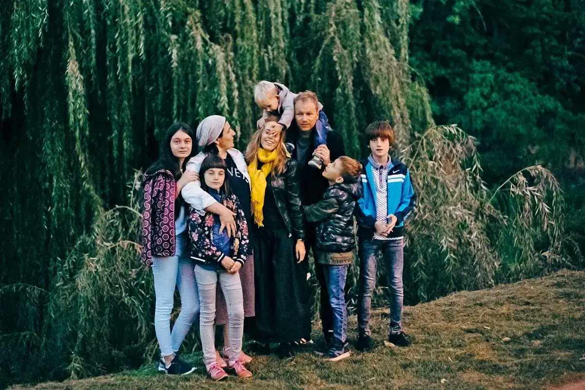 Żona Macieja Stuhra z rodziną pozuje do zdjęcia na tle zieleni.