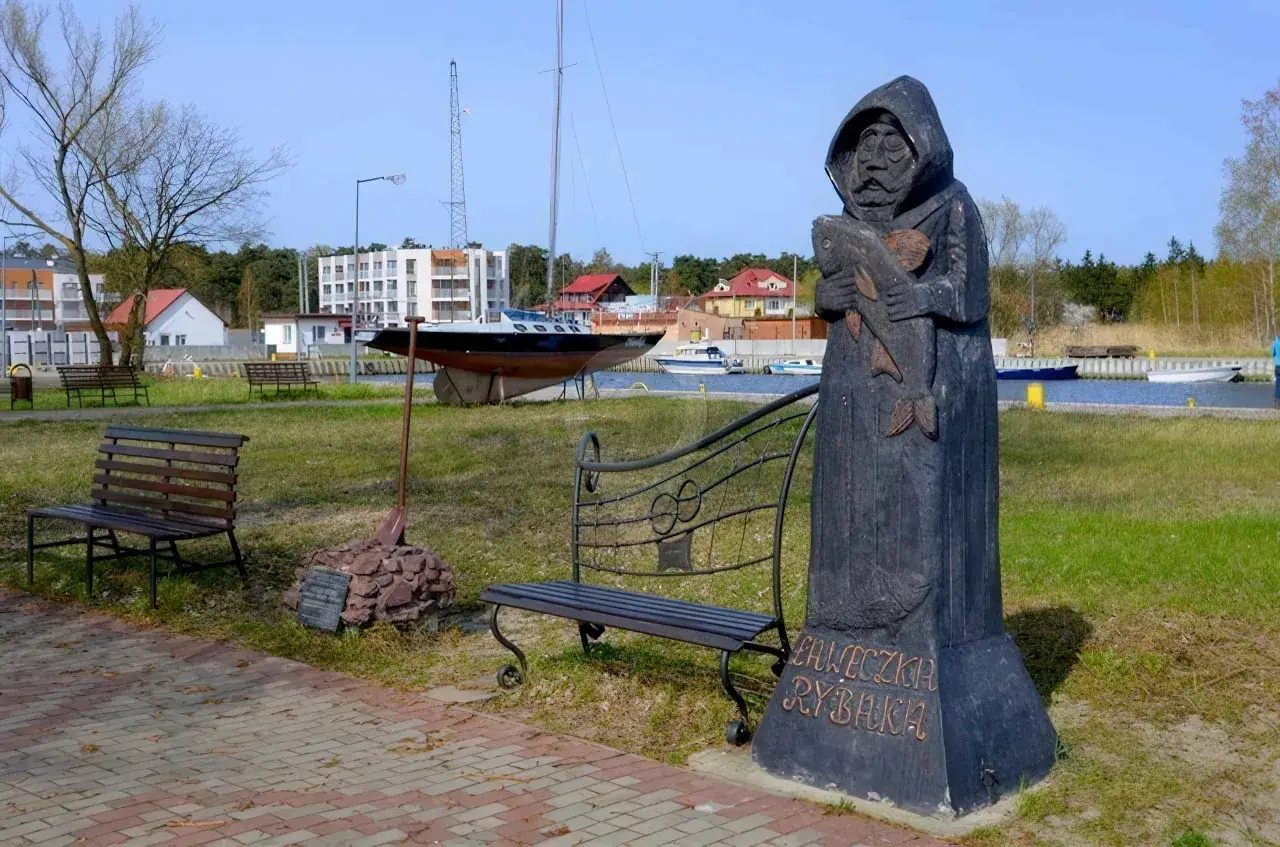 Drewniany pomnik rybaka trzymającego rybę, z napisem