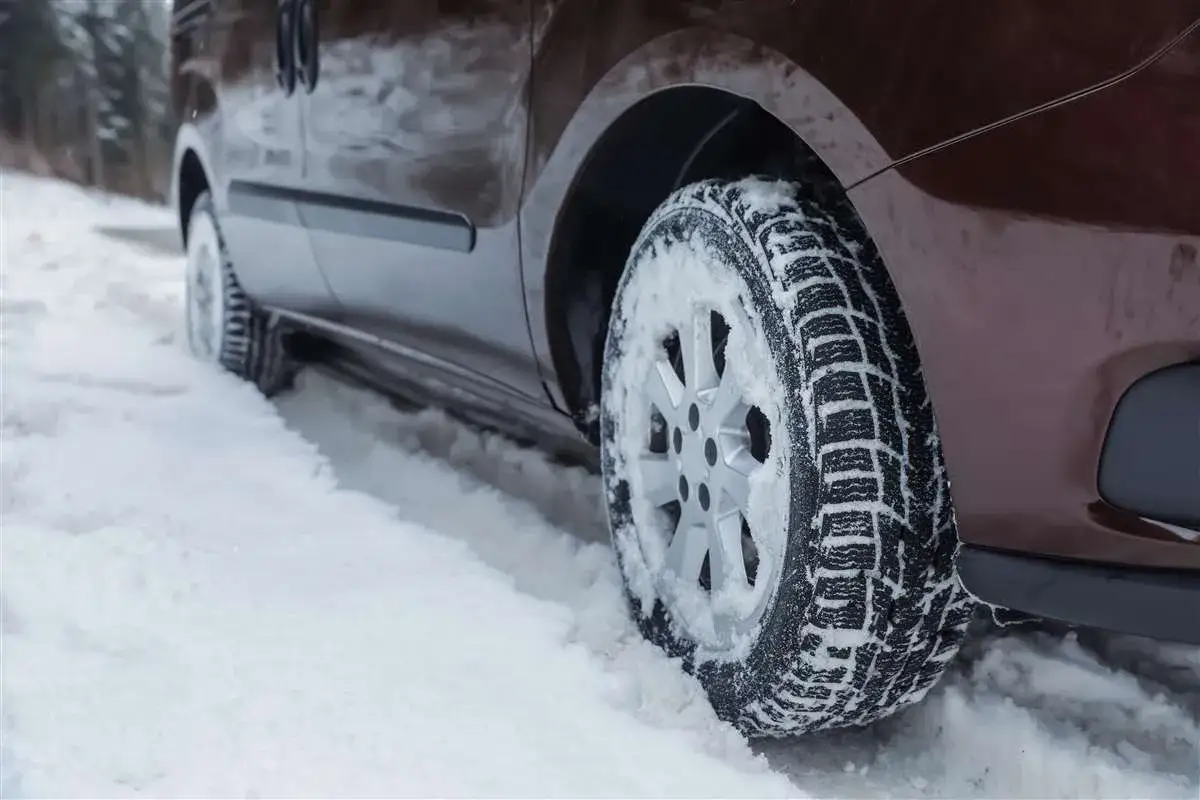 Pneumatici invernali su tutte le ruote affrontano la neve, garantendo aderenza e sicurezza su strade ghiacciate.