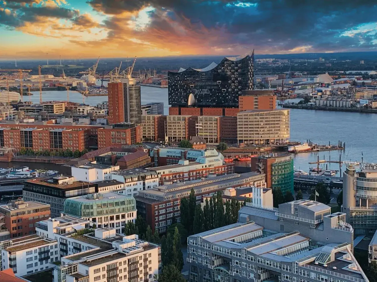 Zachód słońca nad portem w Hamburgu, gdzie nowoczesna architektura i ruchliwy port tworzą tętniące życiem centrum. Hamburg ludność cieszy się widokiem.