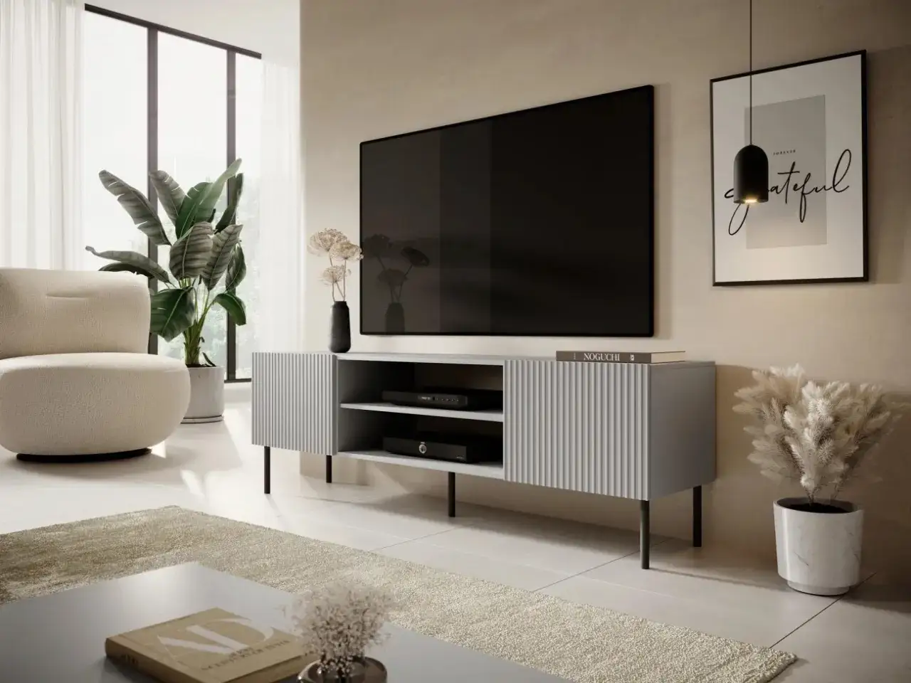 Modern tv möbel i grått med ribbad front. En stor platt-TV hänger ovanför. I rummet finns en beigefärgad fåtölj och en stor grön växt.
